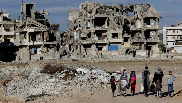 Syrian citizens walk in front of buildings that were destroyed during the battle between the US-backed Syrian Democratic Forces fighters and Islamic State militants in Manbij, northern Syria.