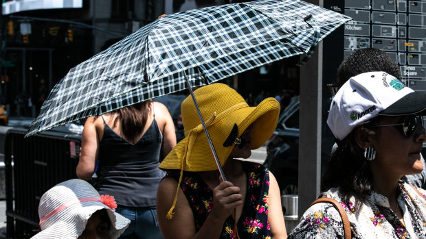 A person holds an umbrella for shade in  Times Square.