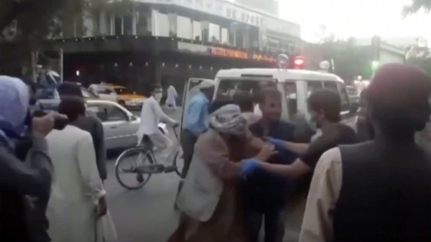 People tend to a wounded person near the site of a deadly explosion outside the airport in Kabul, Afghanistan.