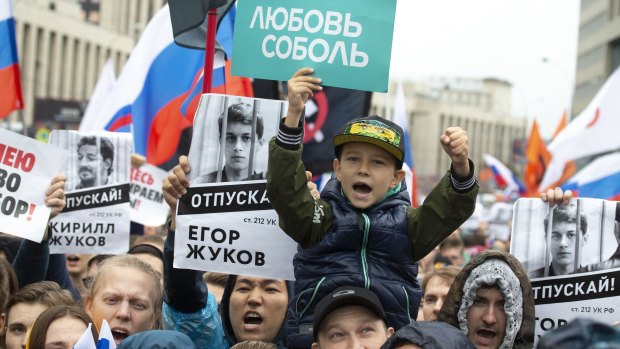 People hold portraits of detained protesters and a boy holds poster reading 'Lyubov Sobol' in Moscow last month.