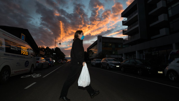 A DHHS worker carries food into the locked down Maribyrnong apartment complex.