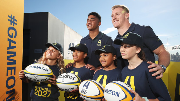 Waratahs player Clem Halaholo (left) and Wallabies back player Reece Hodge (right) pose with young players at the launch of Australia’s Rugby World Cup 2027 bid.