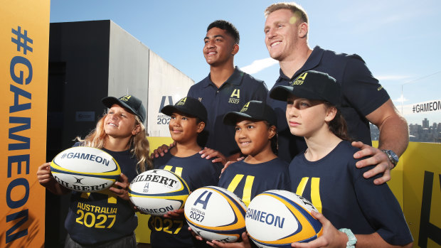 Waratahs player Clem Halaholo (left) and Wallabies star Reece Hodge (right) pose with young players at the launch of Australia’s Rugby World Cup 2027 bid.