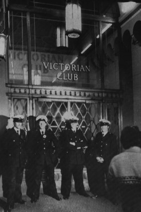 Police stand guard on the main entrance to the Victorian Club.