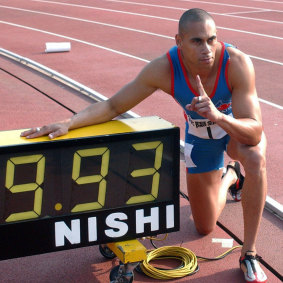 Australian sprinter Patrick Johnson poses next to a clock showing his national record time in 2003.