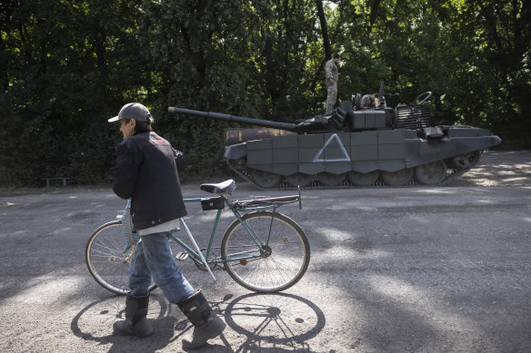 A man pushes a bicycle past a Ukrainian tank in the Sumy region of Ukraine.