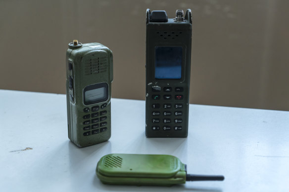 Recovered Russian military radios, standing upright, and a green radio made by Himera, a Ukrainian company that makes $US100 walkie-talkies that can withstand Russian jamming.