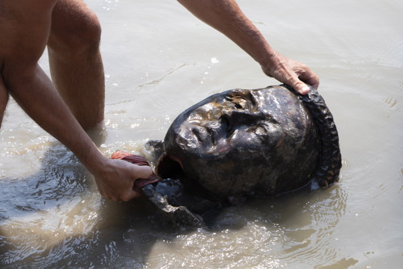 The head of a statue of Queen Victoria is fished from a river in Winnipeg after it was cut off during demonstrations. 