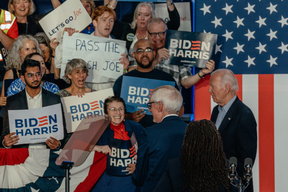 An attendee holds up a sign encouraging President Joe Biden (right) to drop out of the election during a campaign event at Sherman Middle School in Madison, Wisconsin.