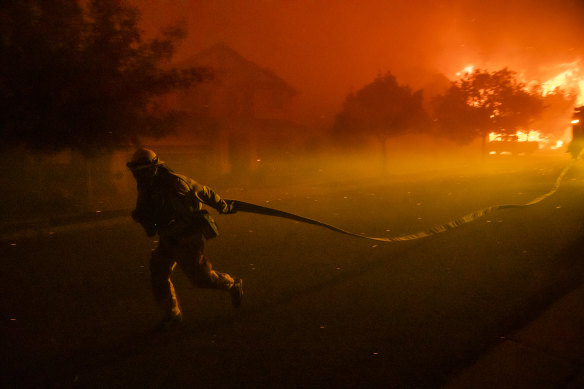 A firefighters drags a hose as he defends the Skyhawk Park neighbourhood of East Santa Rosa.