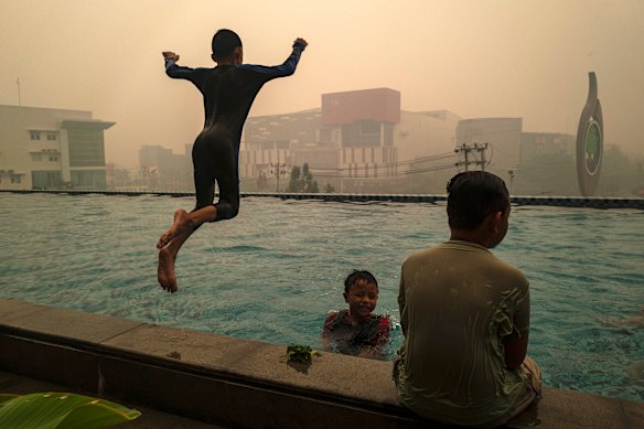 At a hotel in Pontianak, children played in a hotel pool beneath a smoke-filled sky.