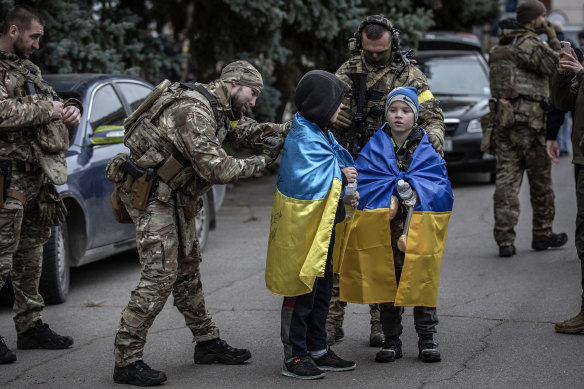 A Ukrainian soldier signs a flag for a child in the main square in the recently liberated city of Kherson, Ukraine, on Sunday, November 13.