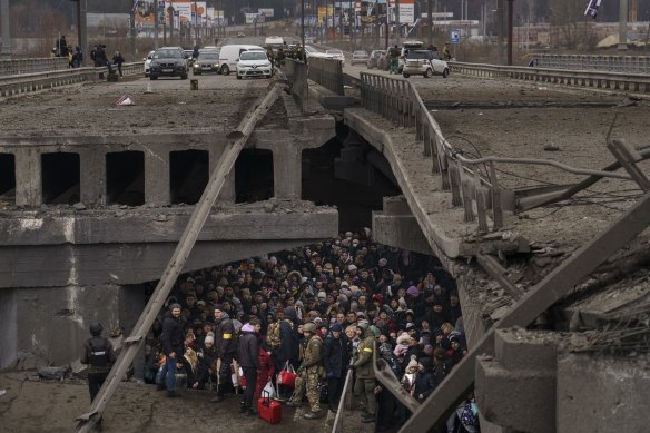 Ukrainians crowd under a destroyed bridge over the Irpin River on the outskirts of Kyiv on March 5, 2022.