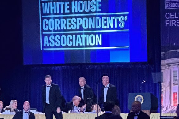 Agentes do Serviço Secreto dos EUA cercam o presidente Donald Trump após um tiroteio fora do salão de baile durante o jantar dos correspondentes na Casa Branca na noite de sábado.