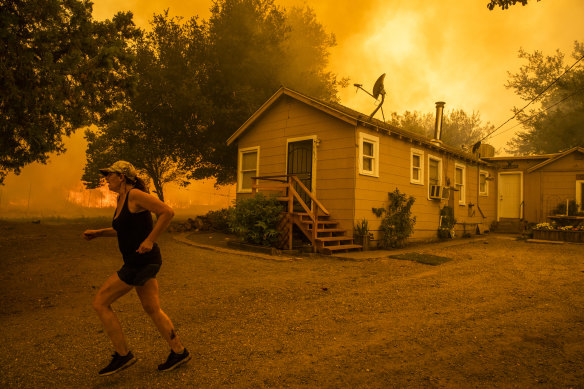 A woman races across her property as the LNU Lightning Complex fire approaches in Vacaville, California.