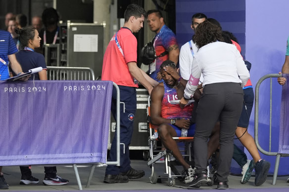 Lyles is taken off the track in a wheelchair after receiving medical attention.