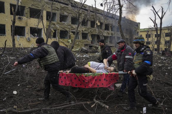 Ukrainian emergency workers and volunteers carry an injured pregnant woman from a maternity hospital damaged by a Russian airstrike.