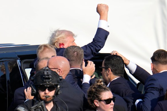 Trump é ajudado a um carro após o tiroteio.