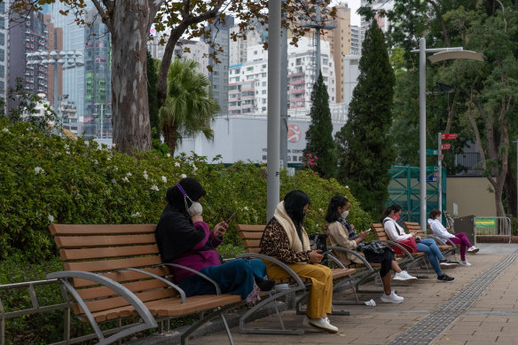 Residents wearing face masks use smartphones at Victoria Park in Hong Kong, where health officials warn that the city is facing a COVID “crisis”.