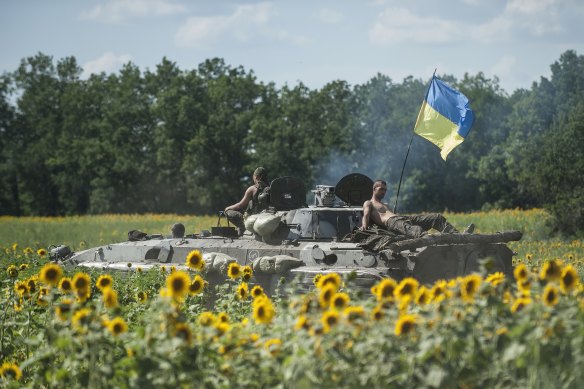  Ukrainian troops ride on an APC with a Ukrainian flag in a field with sunflowers in Kryva Luka, eastern Ukraine, on July 5, 2014.