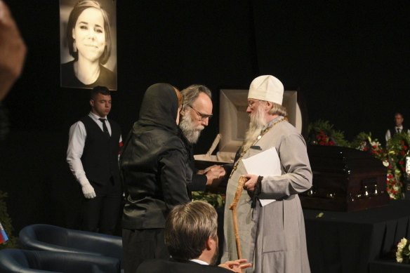 Philosopher Alexander Dugin (centre) speaks with a priest during the final farewell ceremony for his daughter Daria Dugina in Moscow.