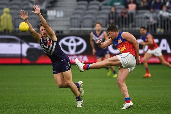 Dayne Zorko kicks the ball as Caleb Serong moves in. 