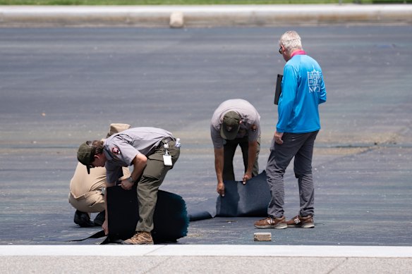 National Park Service workers inspect the damaged lining of the Reflecting Pool on July 20.