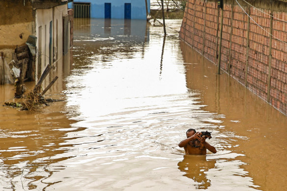 A man carries his dog over floodwaters in Itapetinga, Bahia state, Brazil. Two dams broke Sunday in northeastern Brazil, threatening worse flooding in a rain-drenched region that has already seen thousands forced to flee their homes.