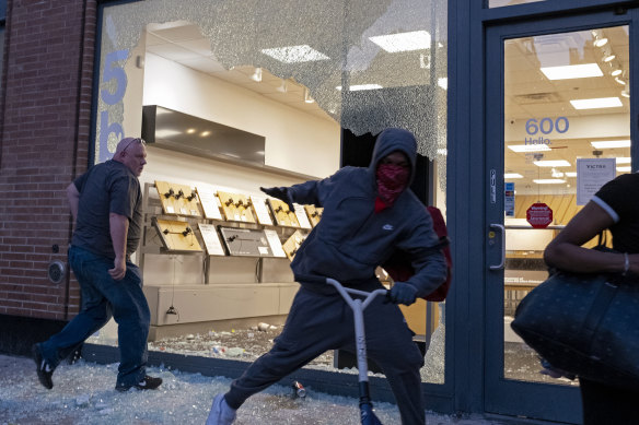 A store is damaged in the Chelsea neighborhood of New York as looters grabbed merchandise along the street.