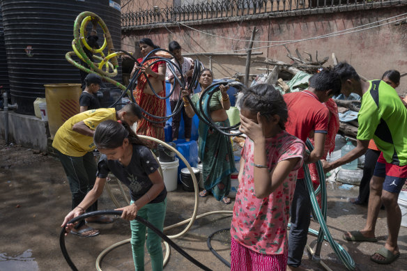 Residents curl up their siphon hoses after a water tanker leaves a Delhi slum.