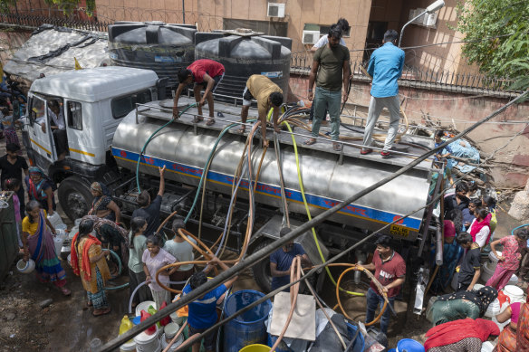 Hoses siphon water from a tanker at a Delhi slum on Saturday.