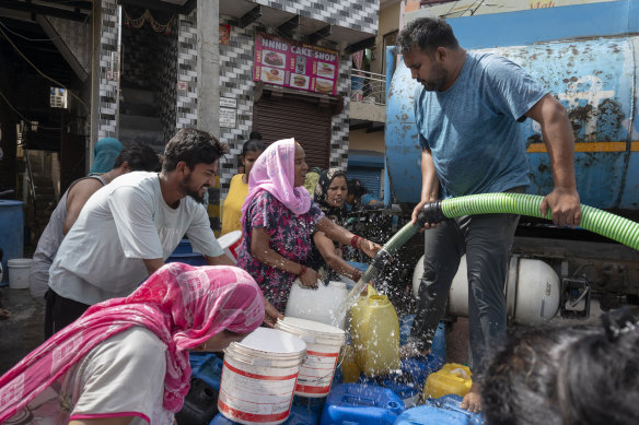 Residents fill their containers from a water tanker.