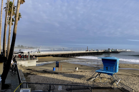 Bystanders looks out at a closed Santa Cruz wharf after the pier partially collapsed and fell into the ocean in Santa Cruz, California.