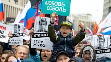 People hold portraits of detained protesters and a boy holds poster reading 'Lyubov Sobol' in Moscow last month.
