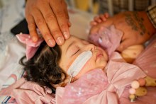 Luna rests as her father, Gerson Maradiaga, caresses her at Children’s Specialised Hospital in New Jersey. 