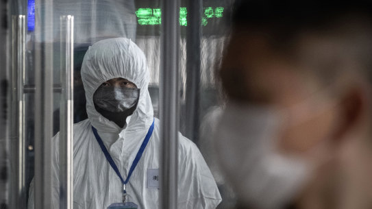 A Chinese health worker waits to check the temperature of travelers  entering a train station during the Chinese New Year.