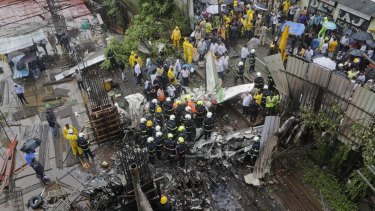 Rescuers stand amid the wreckage of a private chartered plane that crashed in Ghatkopar area, Mumbai.
