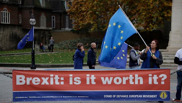 An anti-Brexit supporter holds a European flag by a banner across the street from the Houses of Parliament in London.