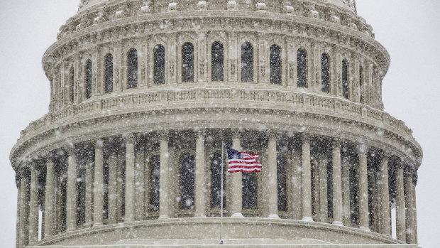 An American flag waves in front of the US Capitol Dome as a winter storm arrives in the region on Sunday.
