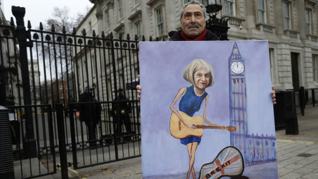 Weird times: Artist Kaya Mar displays his painting of British PM Theresa May in front of Downing Street in London on Tuesday.