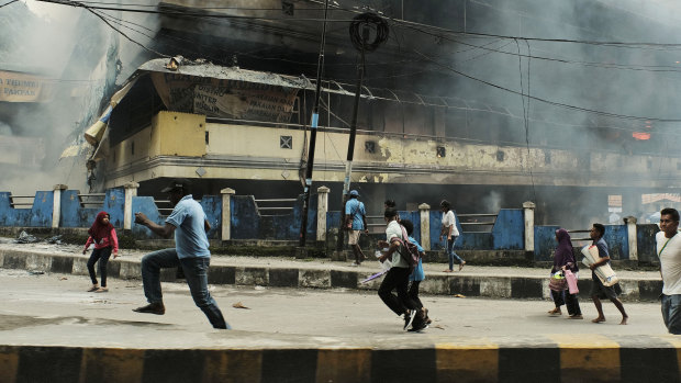 People flee as a local market in Fakfak burnt on Wednesday.