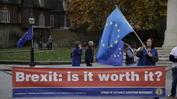 An anti-Brexit supporter holds a European flag by a banner across the street from the Houses of Parliament in London.