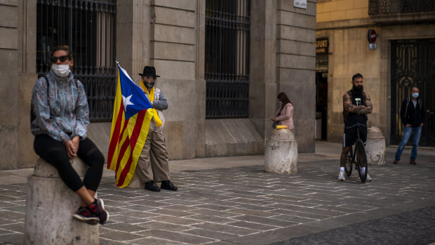 A man holding an "estelada" or independence flag waits for a protest to condemn a police raid on Catalan separatists in Barcelona, Spain.