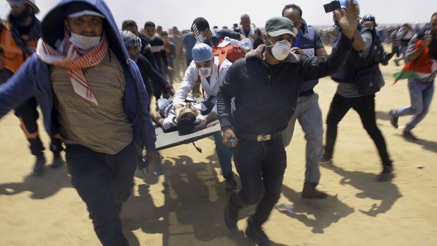 Palestinian medics and protesters evacuate a wounded youth from the clashes in Gaza.
