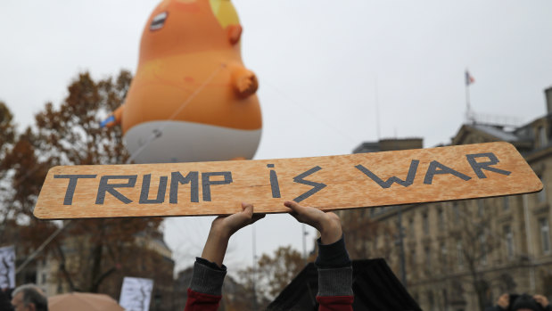 An anti-Trump placard is held in front of an inflatable blimp depicting US President Donald Trump in Paris on Sunday.