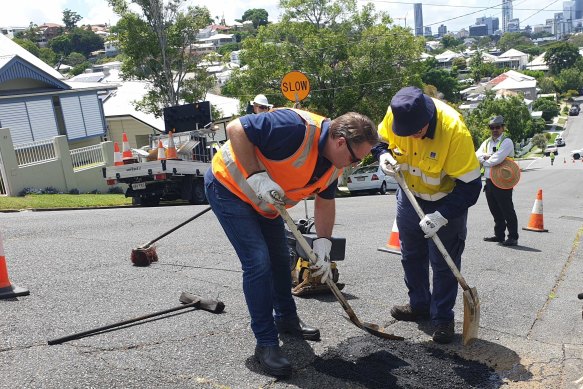 Lord mayor Adrian Schinner helping to fill a pothole at Paddington.