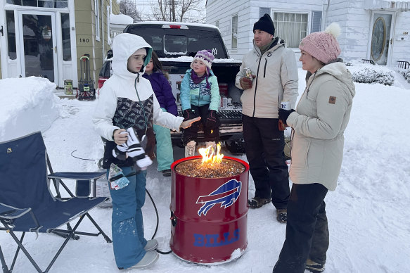 A group of neighbours gather around a fire pit on Culver Road after clearing snow in Buffalo.