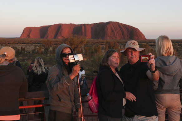 Tourists take photos during sunrise over Uluru on Saturday, the first morning after the climb was permanently closed.