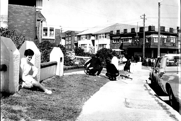Passers-by shelter behind fences near the scene of the siege in Hastings Parade, Bondi on September 9, 1969