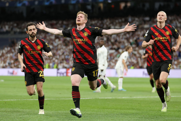 Kevin De Bruyne celebrates with teammates Bernardo Silva and Erling Haaland.